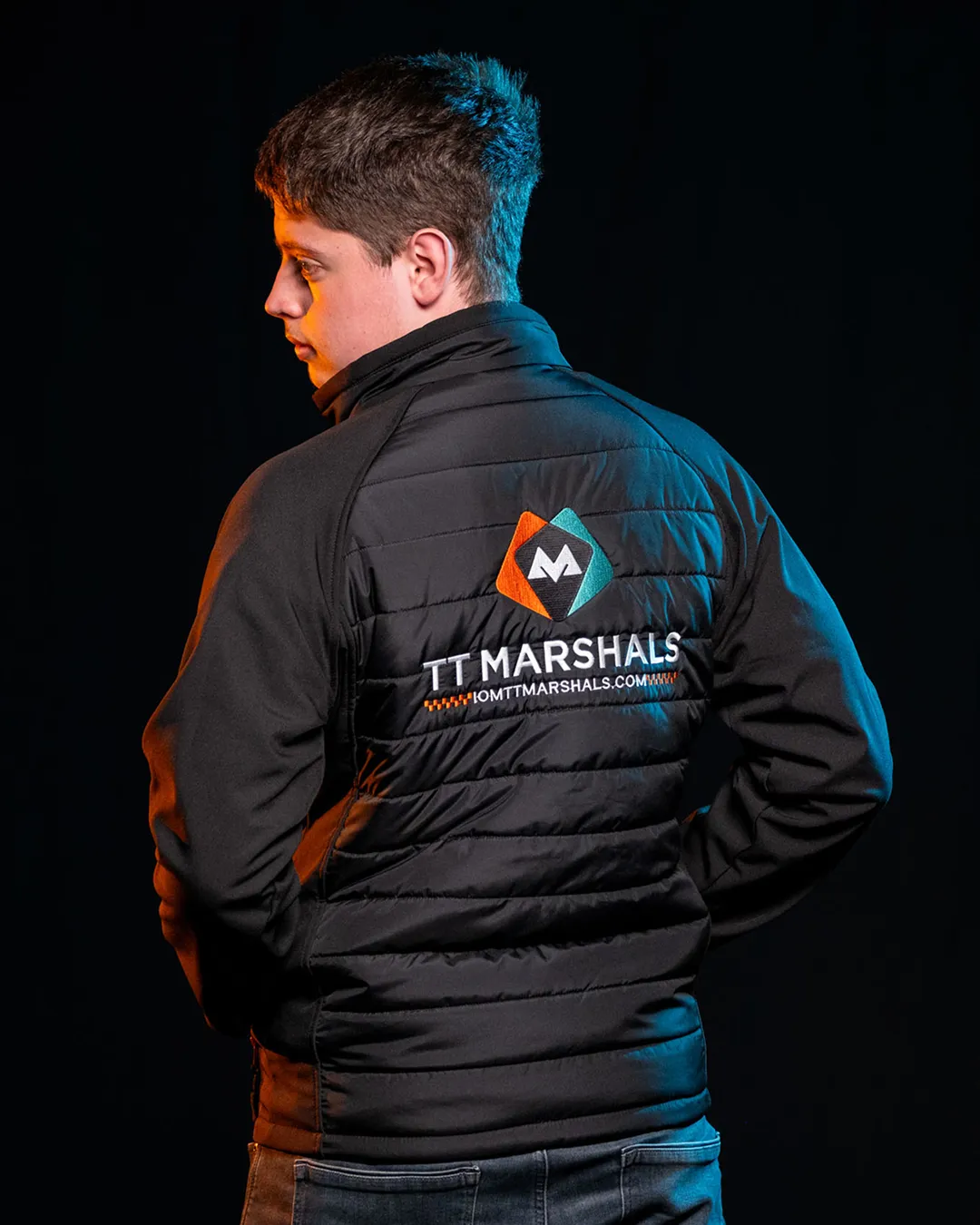 Deane Corlett-Aspell wearing the official TT Marshals 2026 black softshell jacket, featuring the TT Marshals logo. Exclusive marshal merchandise for the Isle of Man TT 2026.